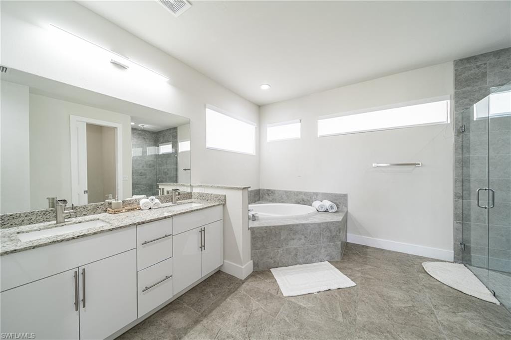 Expansive bathroom featuring a dual vanity with white cabinetry and granite countertops