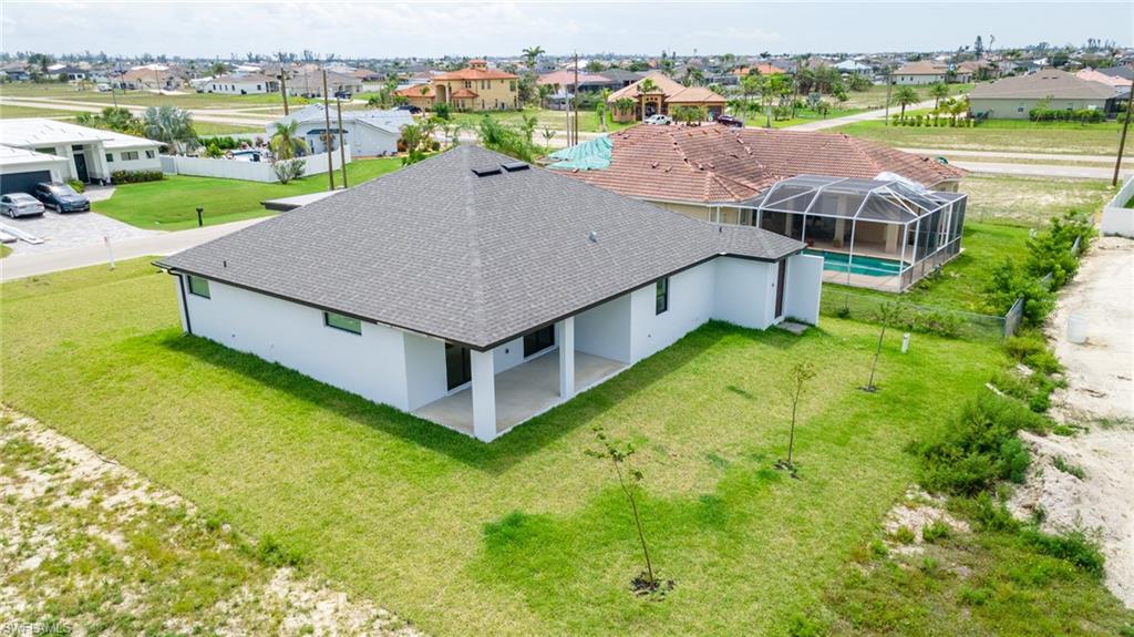 Modern residence featuring a neutral exterior, dark shingle roof, and a covered back patio