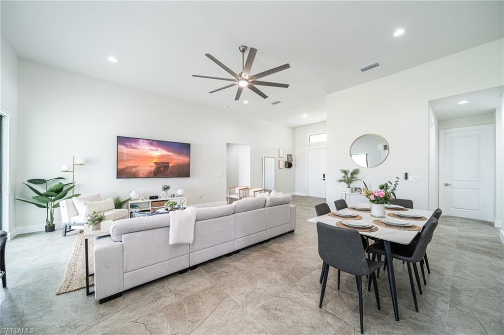 Open-concept living space with light gray tile flooring, recessed lighting, and high ceilings