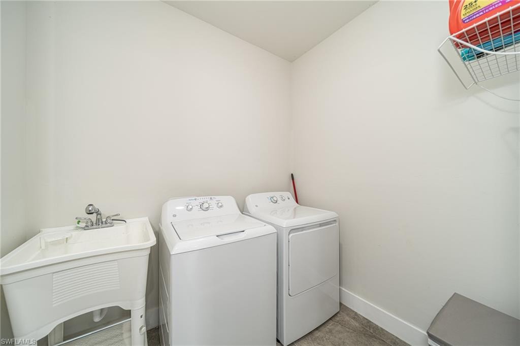 Dedicated laundry area featuring a utility sink with dual-handle faucet, a top-loading washing machine, and a front-loading dryer
