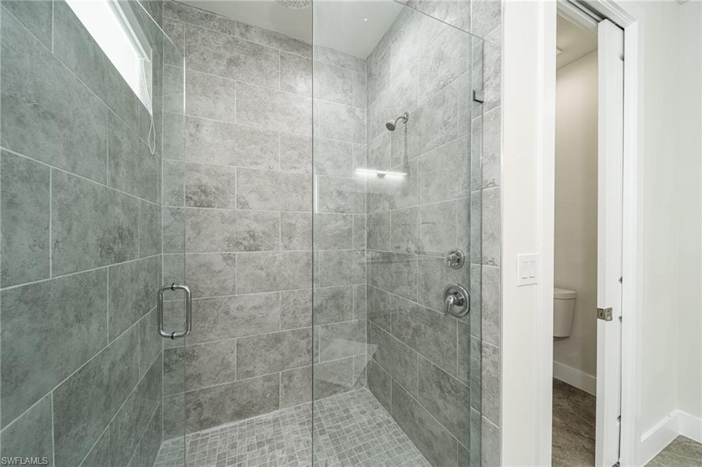 Walk-in shower featuring full-height tiled walls, a glass enclosure, and a mosaic tile floor