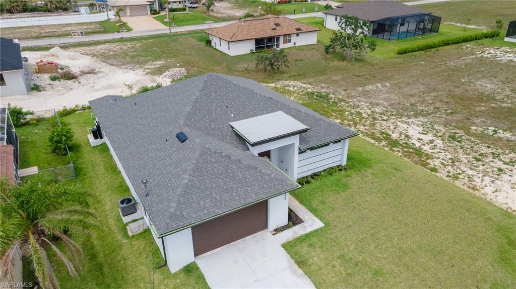 Contemporary-style residence featuring a dark asphalt shingle roof and a concrete driveway