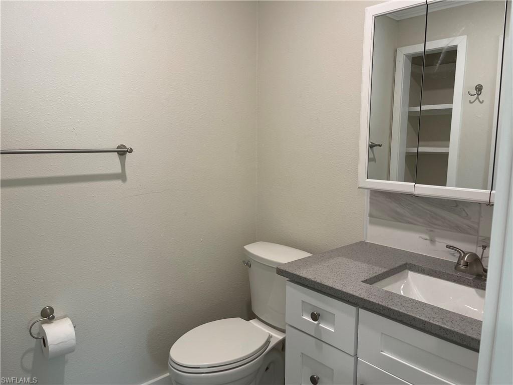 Bathroom vanity with a gray speckled countertop, white cabinetry, and brushed nickel hardware