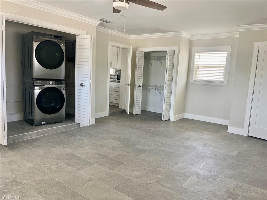Spacious room featuring light gray tile flooring, crown molding, and a ceiling fan