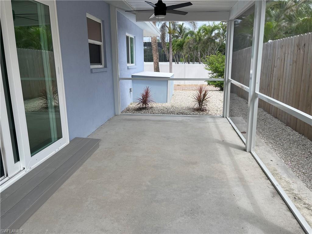 Screened patio with concrete flooring, modern ceiling fan, and composite step leading to sliding glass doors