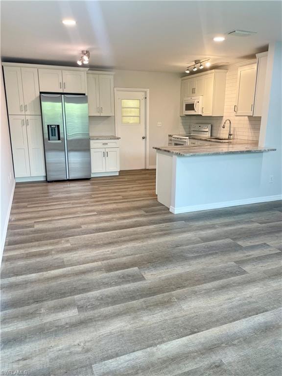 Spacious kitchen featuring white cabinetry, light-toned countertops, a stainless steel refrigerator, and wood-finish flooring