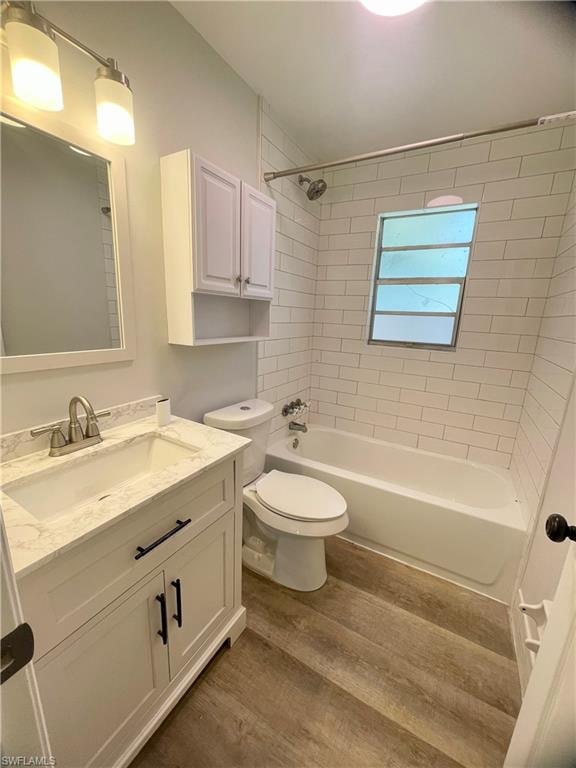 Bathroom featuring a white vanity with a stone-finish countertop and undermount sink, brushed nickel faucet, and wood-finish flooring
