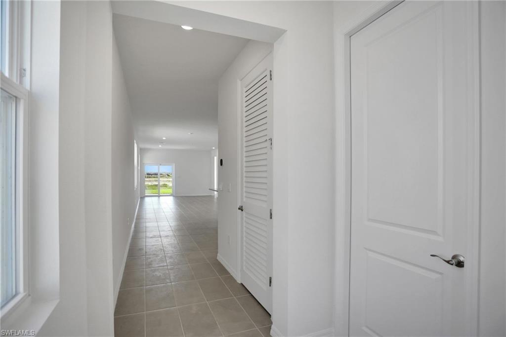 Hall with light tile patterned flooring and recessed lighting