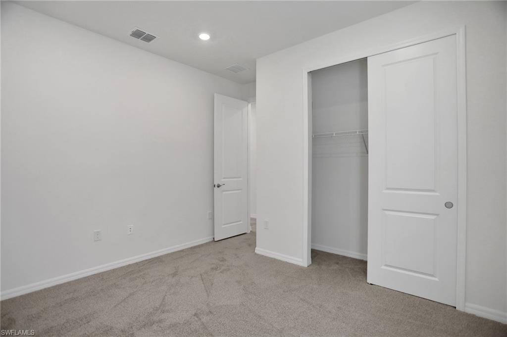 Unfurnished bedroom with light carpet, a closet, and recessed lighting
