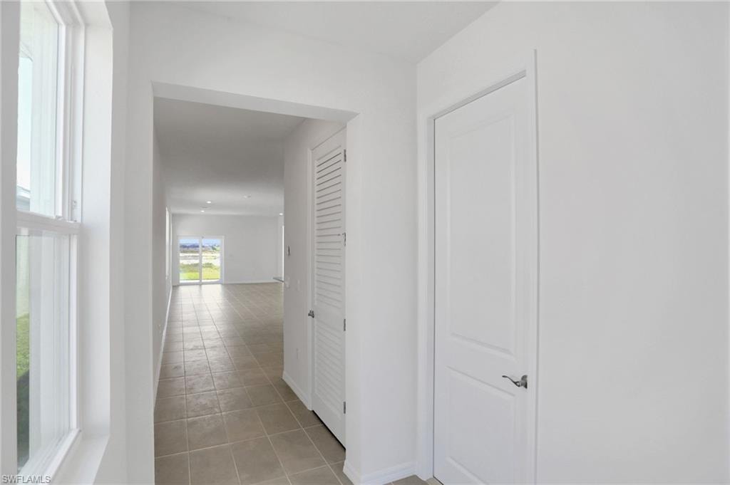 Corridor with light tile patterned floors and baseboards