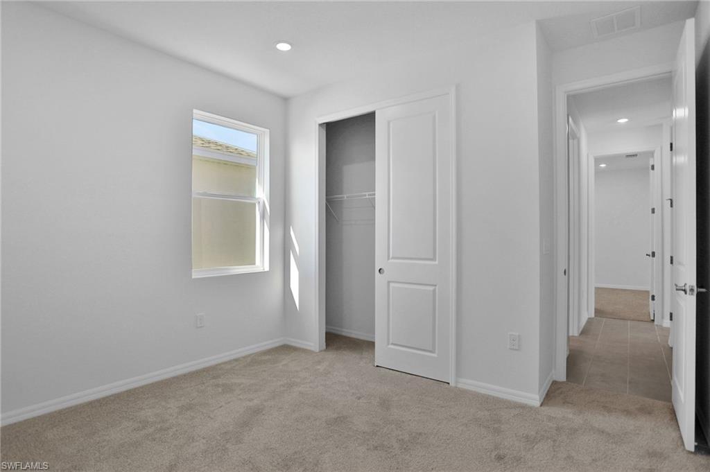 Unfurnished bedroom with light colored carpet, a closet, and recessed lighting