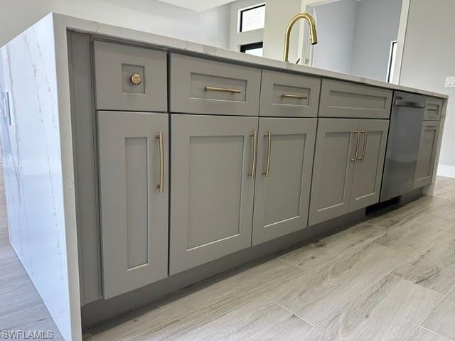 Kitchen featuring pendant lighting, an island with sink, stainless steel appliances, light wood-style flooring, and light stone countertops