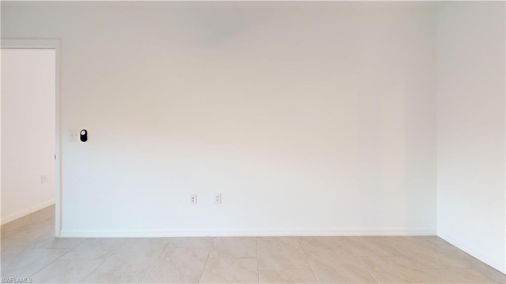 Light-toned tile flooring, white baseboards, and a doorway with white trim