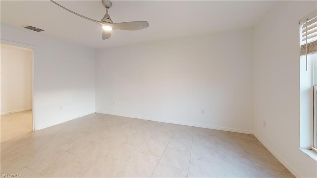 Spacious room featuring neutral-toned tile flooring, a modern ceiling fan with integrated lighting, and a white interior door frame