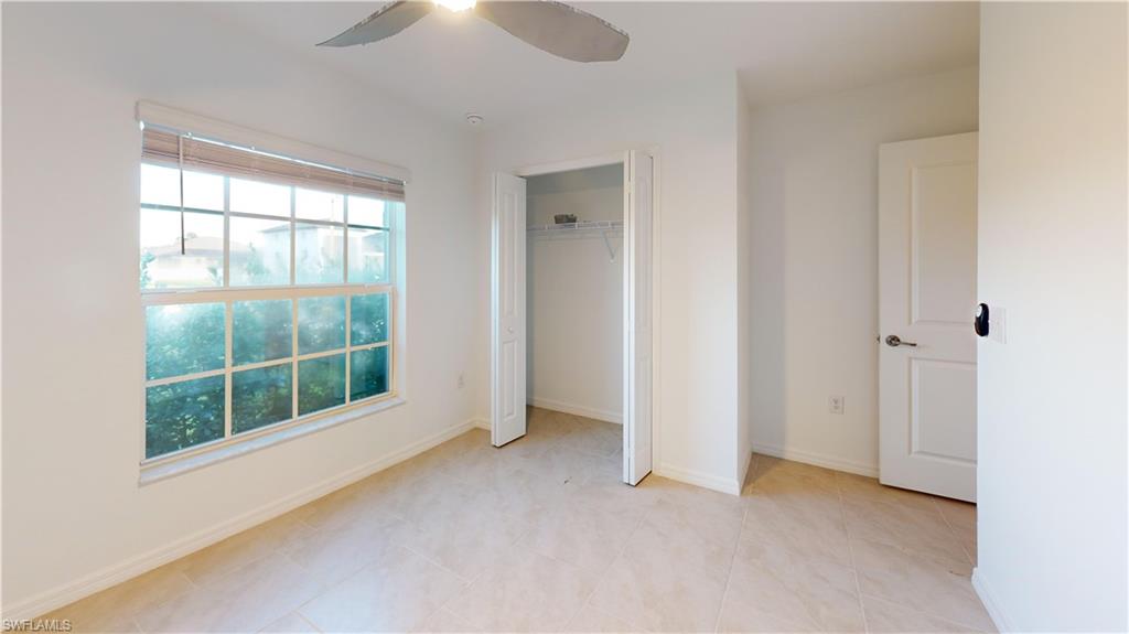 Neutral-toned tile flooring throughout this room, featuring a large window with horizontal blinds