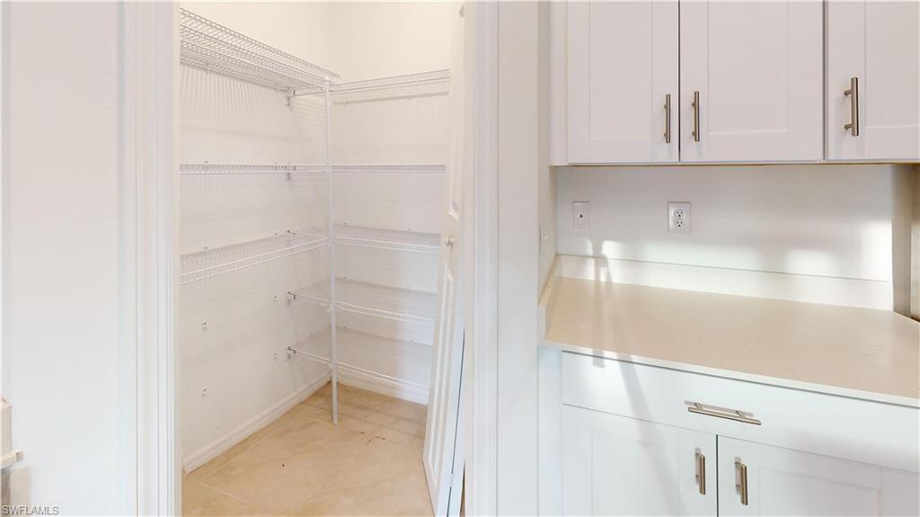 Spacious pantry with wire shelving, light-toned tile flooring, and white trim molding