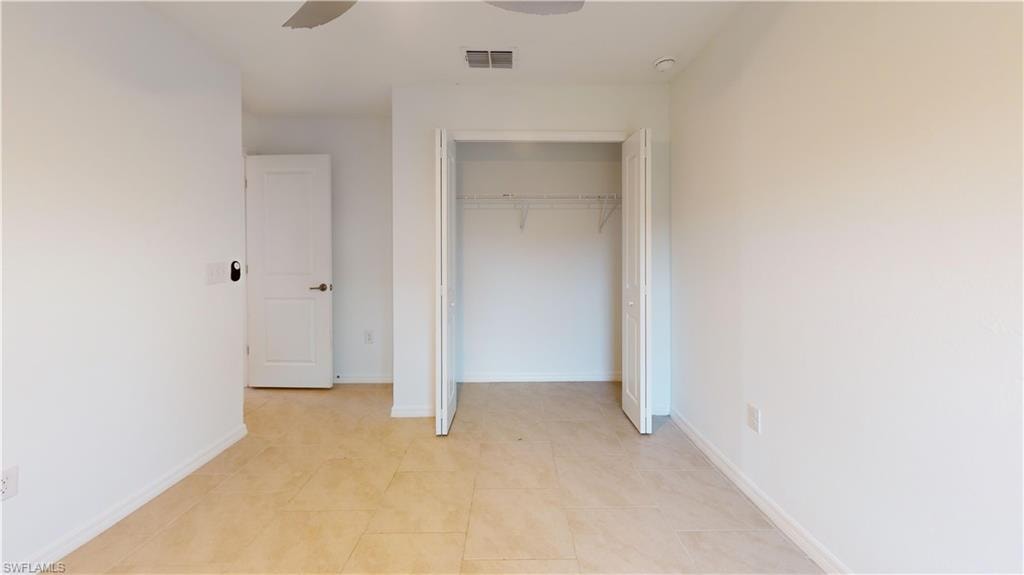 Neutral wall tones and tile flooring define this room, featuring a bifold door closet with wire shelving and a panel door entry