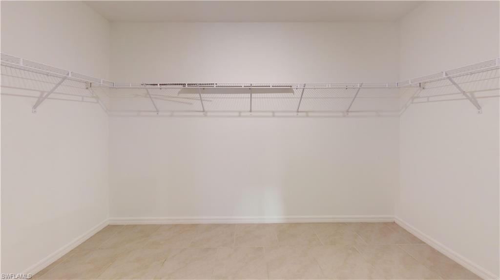 Walk-in closet featuring light-toned tile flooring, white baseboards, and comprehensive wire shelving system