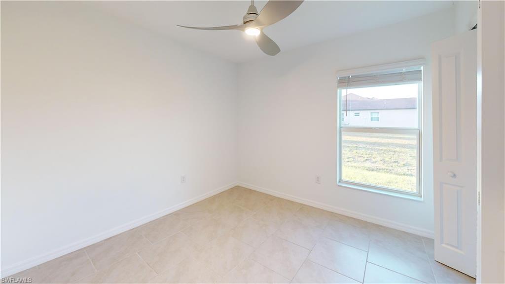Spacious room featuring neutral-toned tile flooring, a large window with horizontal blinds, and a contemporary ceiling fan