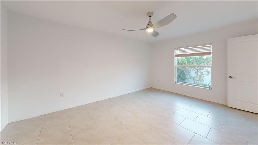 Bright interior space featuring light-toned tile flooring, a modern ceiling fan with integrated lighting, a rectangular window with horizontal blinds, and a contemporary paneled interior door