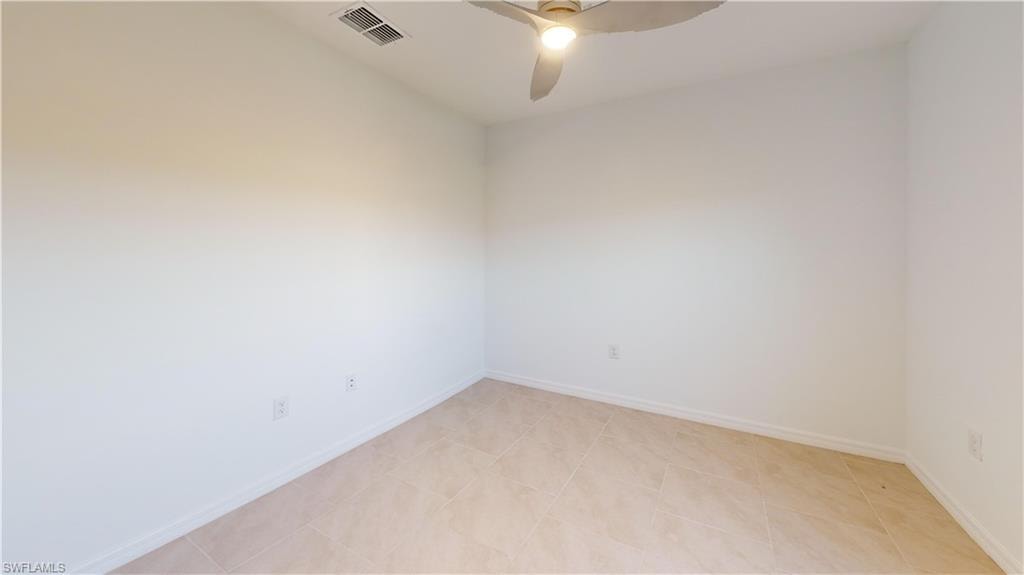 Interior room featuring neutral-toned tile flooring and white baseboards