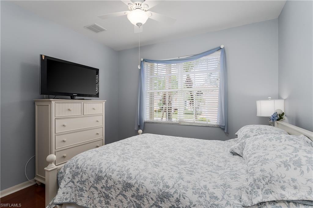 Ceiling fan with integrated lighting, window with horizontal blinds, wall-mounted light fixture, and wood-finish flooring