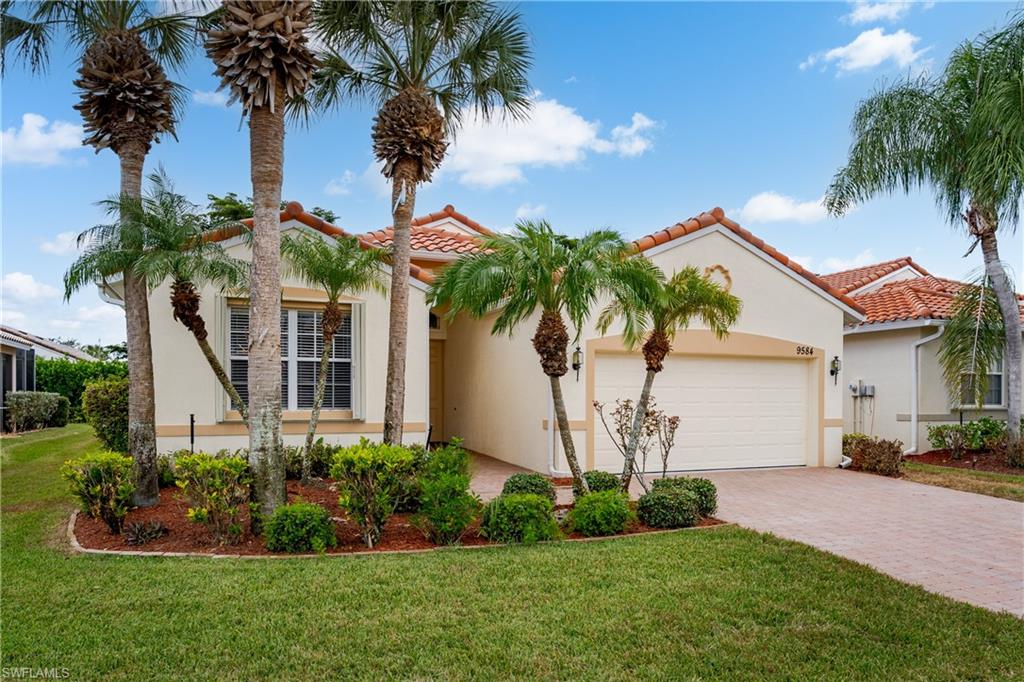 Stucco exterior with a terracotta tile roof, paver driveway, and an integrated garage
