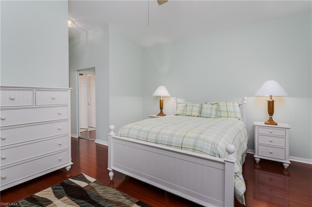 Vaulted ceiling, dark wood-finish flooring, and mirrored closet doors