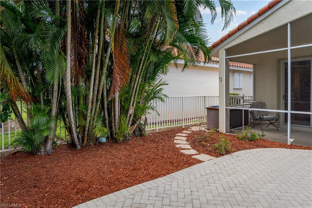 Screened patio with a tile roof, paver flooring, mulched landscaping, and mature palm trees