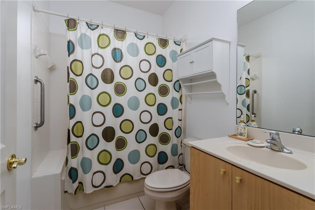 Bathroom featuring a single vanity, a built-in medicine cabinet, and a tiled shower with grab bar