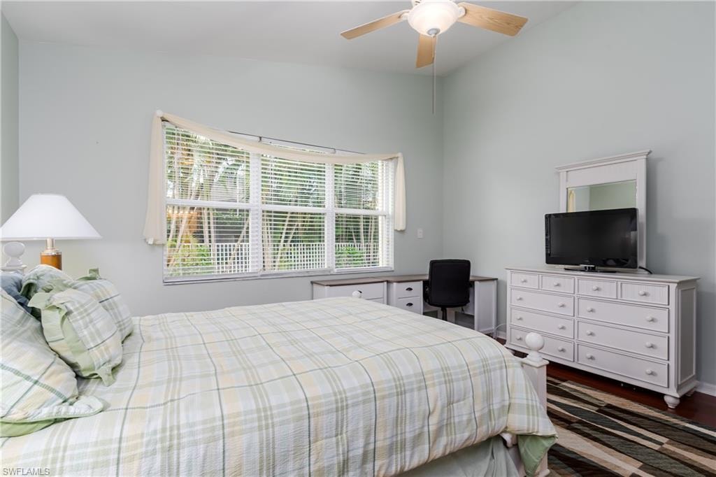 Vaulted ceiling with a ceiling fan, window with horizontal blinds, built-in desk with storage, and dark wood-finish flooring