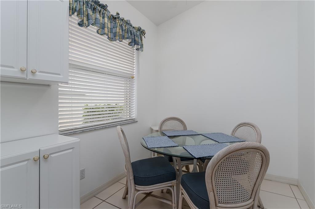 Built-in cabinetry with gold-tone hardware, window with horizontal blinds, and tiled flooring