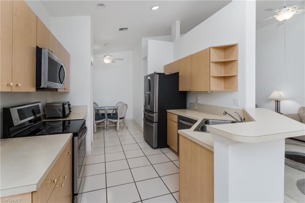 Kitchen featuring light wood-finish cabinetry, light-toned countertops, tile flooring, and a stainless steel appliance package