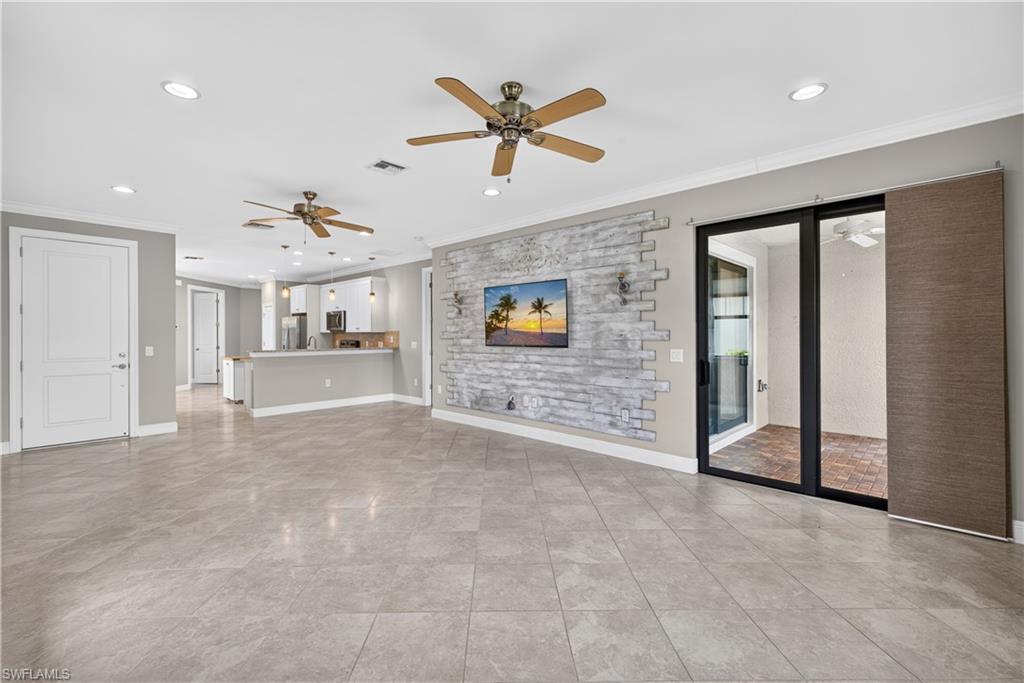 Living room with impact resistant sliding doors leading to the extended lanai, upgraded tile floors, crown molding and 5 1/4" baseboards.