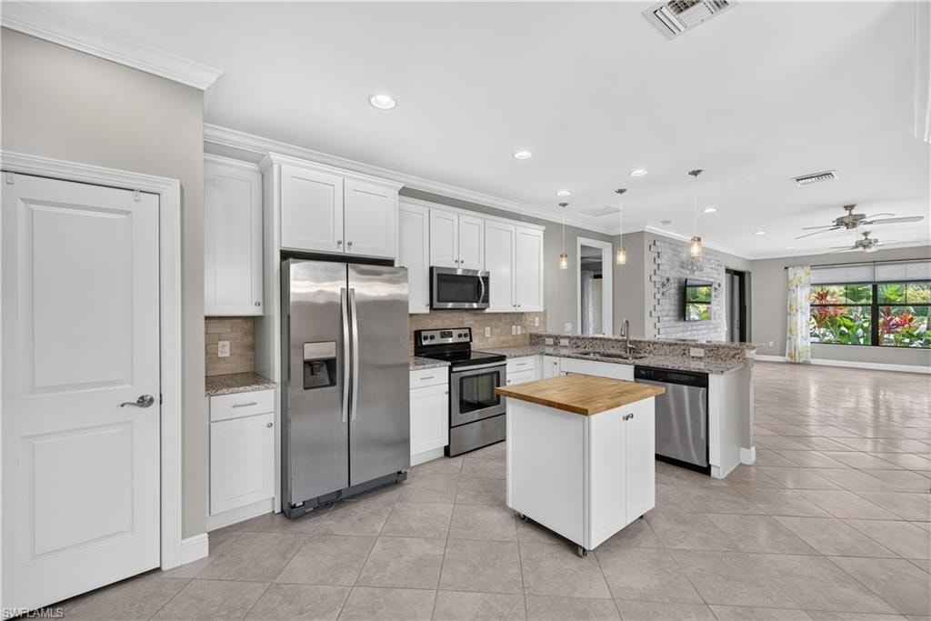 Kitchen featuring white cabinetry, stainless steel appliances, granite countertops, and a tiled backsplash