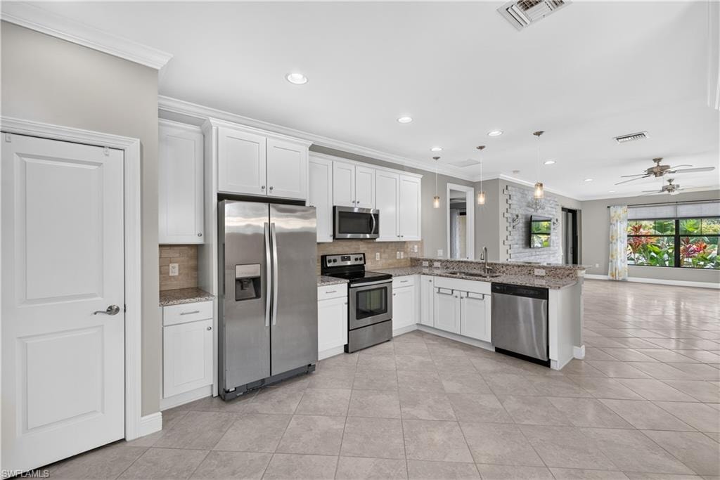 Kitchen featuring white cabinetry, stainless steel appliances, speckled countertops, tile flooring, and recessed lighting