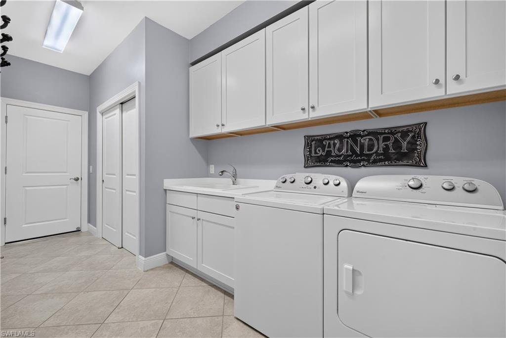 Dedicated laundry room featuring white cabinetry, a utility sink, and light tile flooring