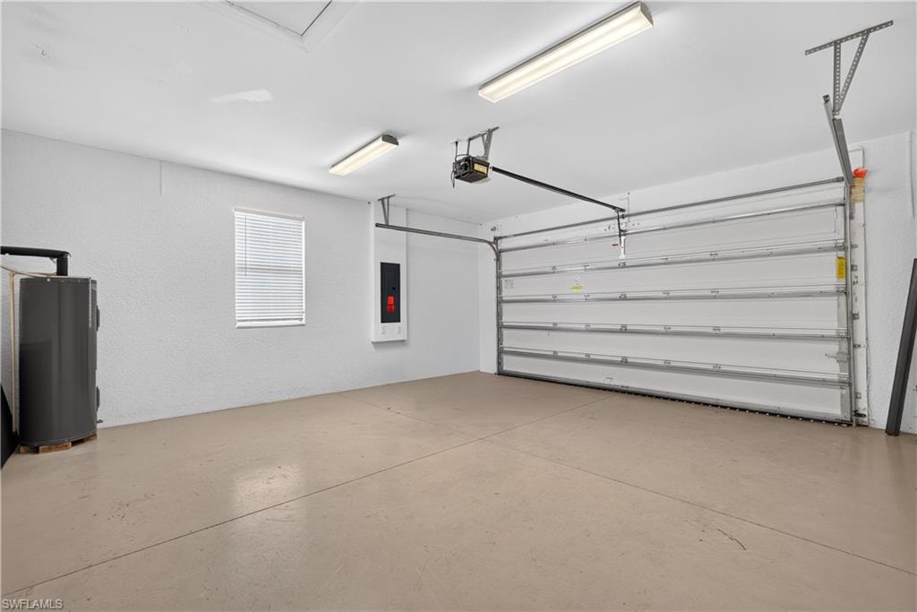 Spacious garage featuring a sectional overhead door with automatic opener, concrete flooring, window with blinds, and fluorescent lighting
