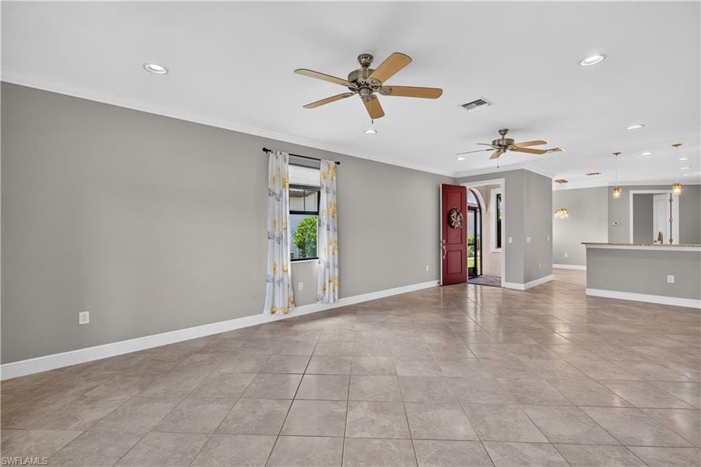 Living room with impact resistant front door leading to the screened entrance, upgraded tile floors, crown molding and 5 1/4" baseboards.