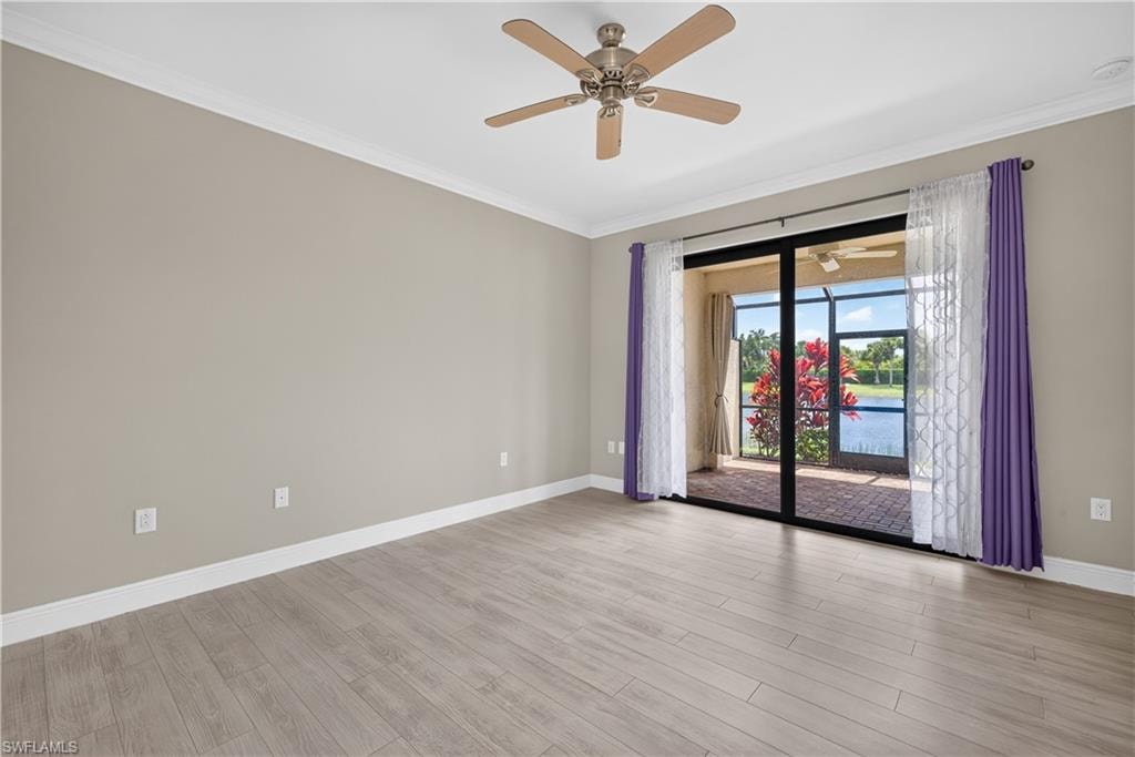 Spacious bedroom with impact resistant glass doors opening to a screened lanai and water views.