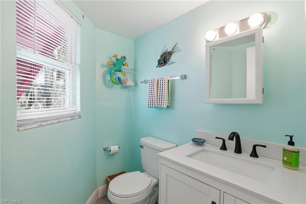 Bathroom featuring a white vanity with integrated sink, matte black faucet, and white countertop - Virtually Edited Image