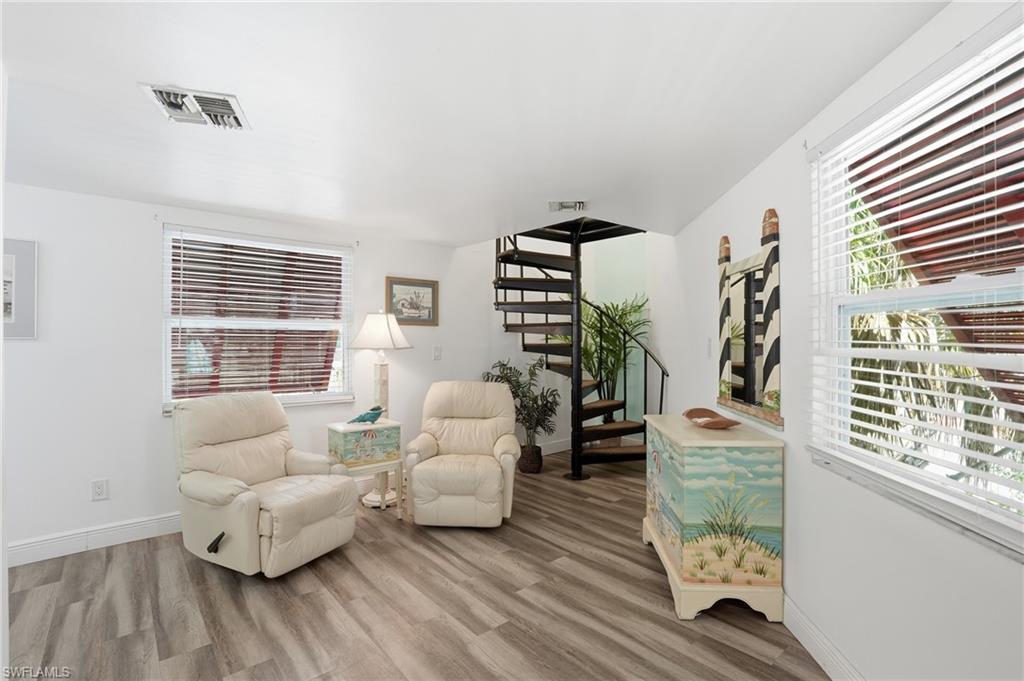 Interior space featuring wood-finish flooring, white walls, and white window blinds - Virtually Edited Image