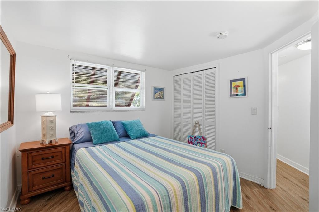 Bedroom featuring wood-finish flooring, white walls, and a white ceiling - Virtually Edited Image