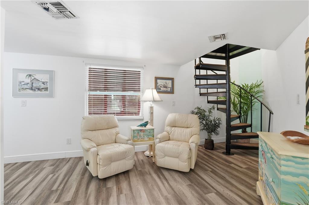 White walls and wood-finish flooring complement a prominent black spiral staircase - Virtually Edited Image