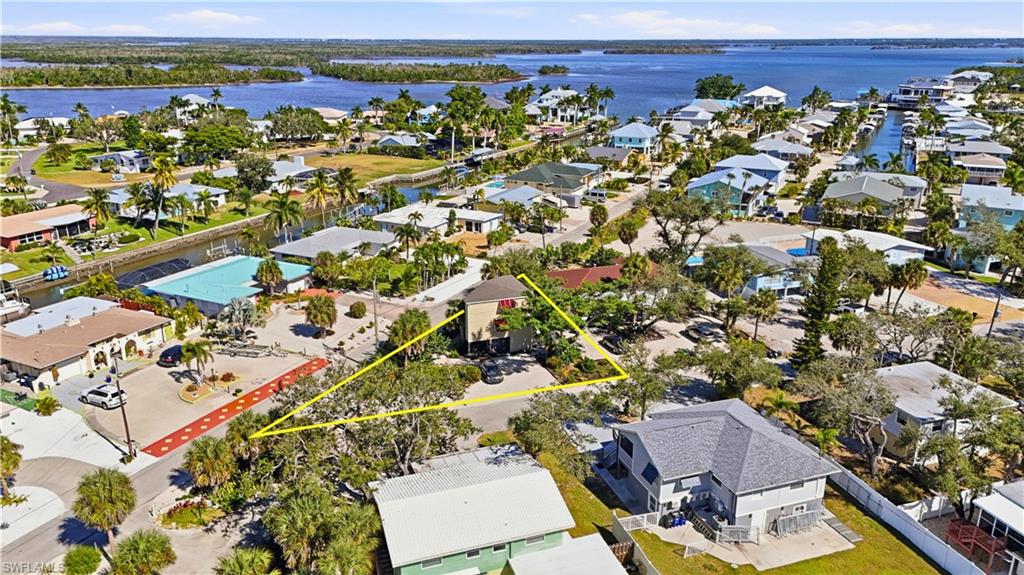 Aerial perspective of suburban area with a nearby body of water and property boundaries highlighted - Virtually Edited Image