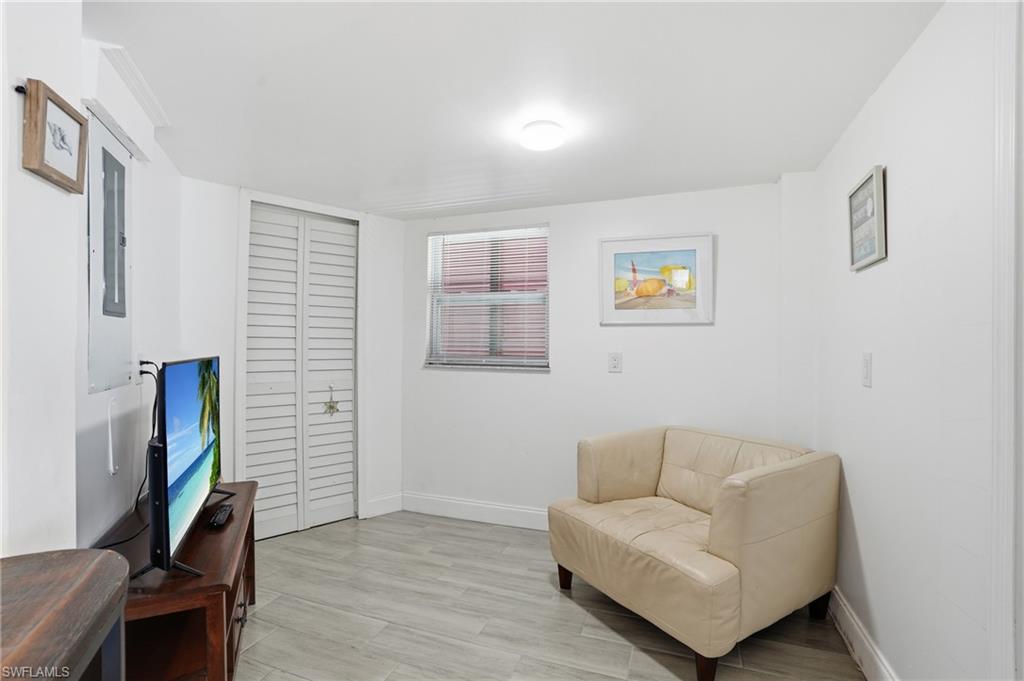 Interior room featuring wood-finish flooring, white painted walls, and a ceiling-mounted light fixture - Virtually Edited Image