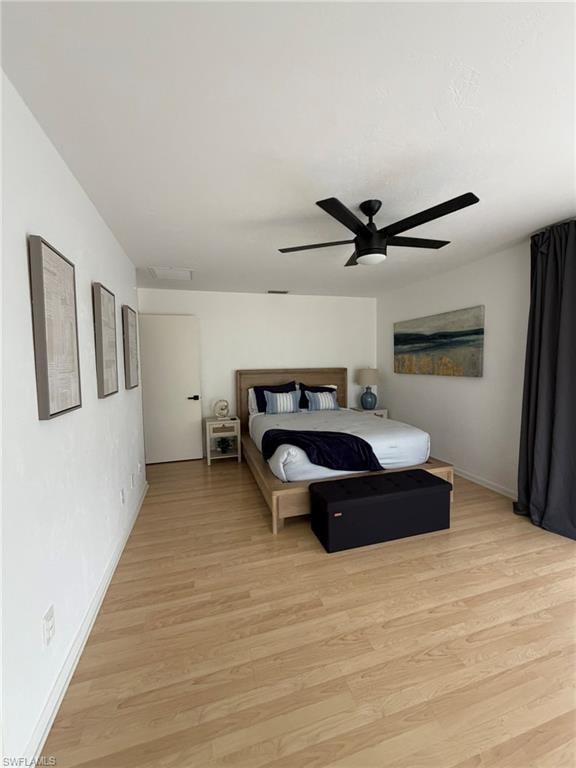 Spacious room featuring wood-finish flooring, a modern black ceiling fan with integrated lighting, and white walls