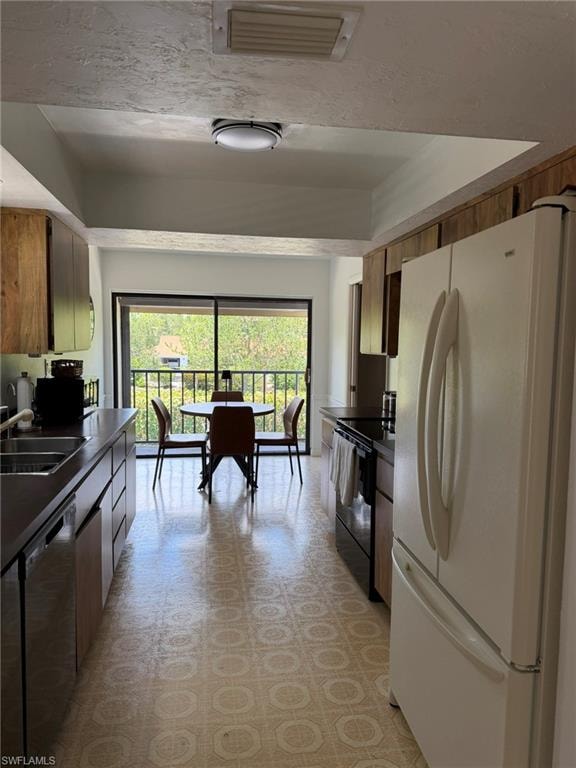 Galley kitchen featuring wood cabinetry, dark countertops, and patterned flooring