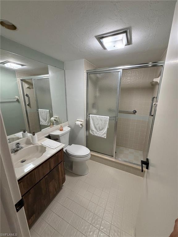 Bathroom featuring a wood-finish vanity with an integrated sink, a rectangular mirror, a toilet, a glass-enclosed shower with tiled walls, and square floor tiles