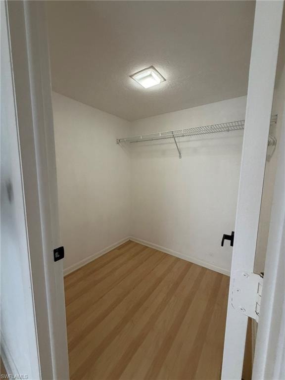 Walk-in closet featuring light wood-finish flooring, white walls, a built-in wire shelving system, and a recessed ceiling light fixture